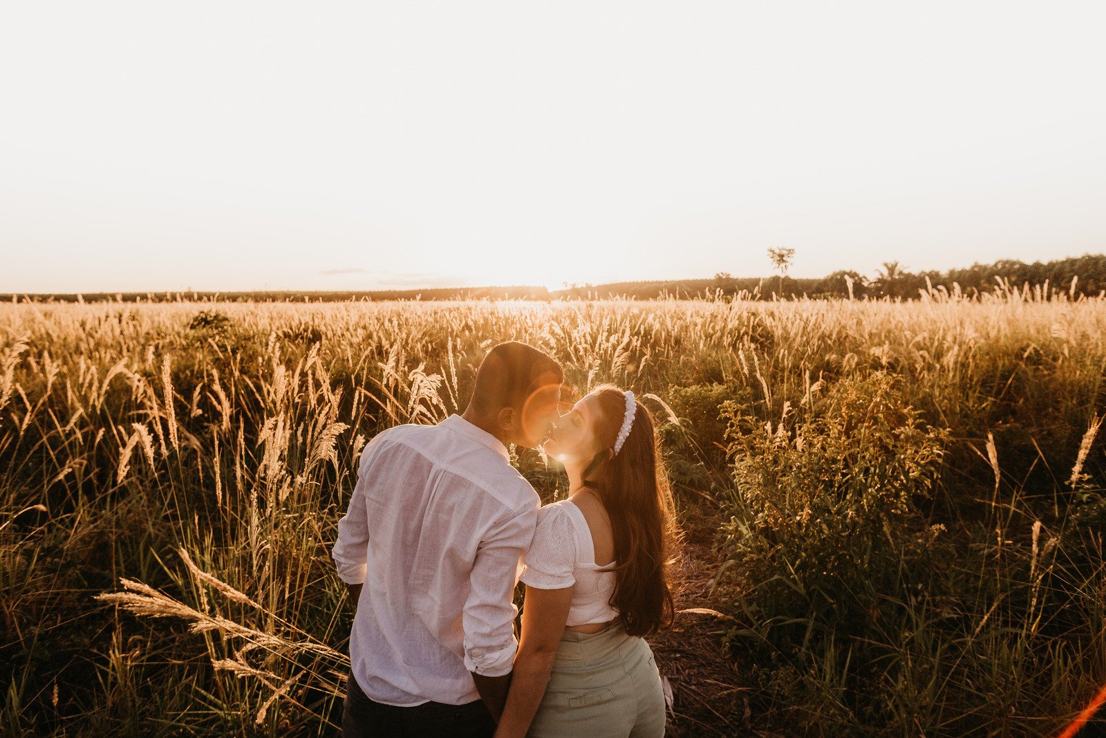 Casal apaixonado beijando no vasto campo ao pôr do sol - Fotos do Canva