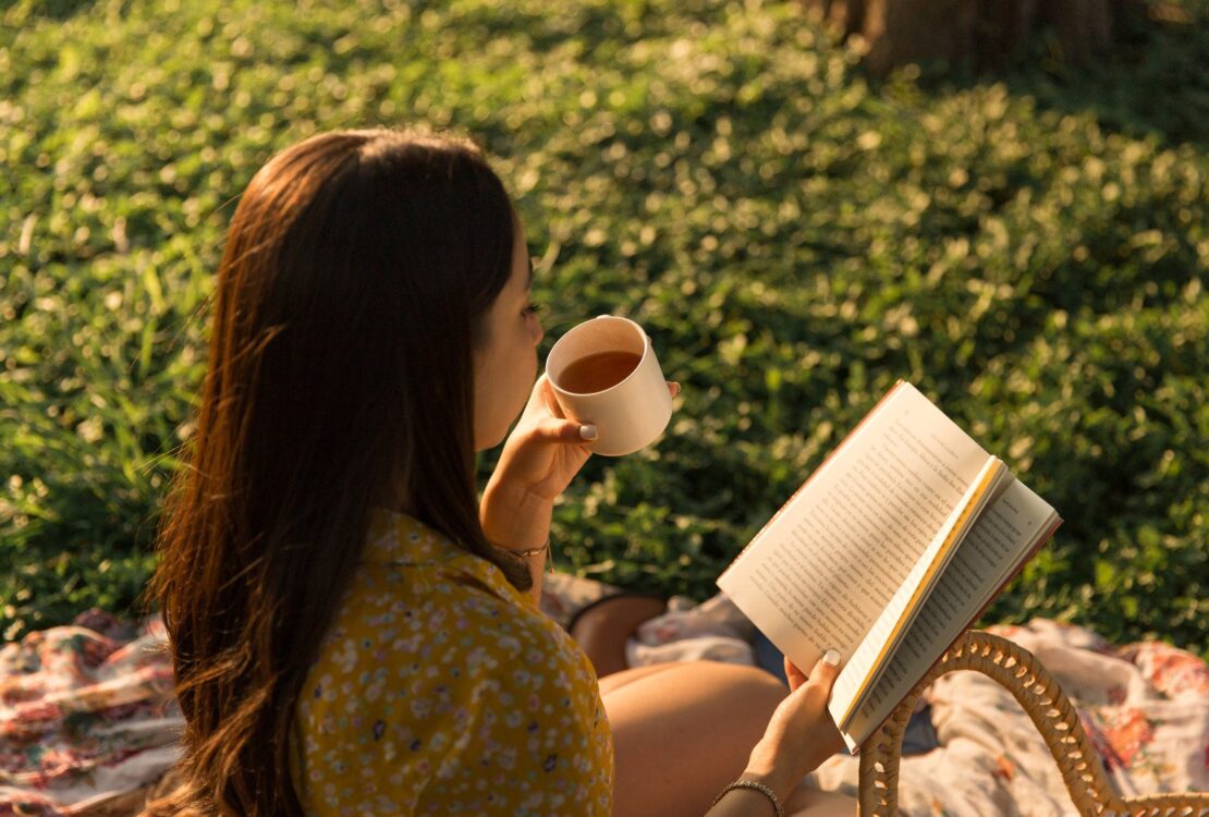 Mulher bebendo chá e lendo um livro, foto de alto ângulo - Fotos do Canva