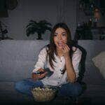 Mulher jovem assistindo TV no sofá à noite - Fotos do Canva