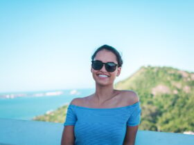 Mulher sorridente usando blusa ombro a ombro listrada cinza e óculos de sol pretos - Fotos do Canva