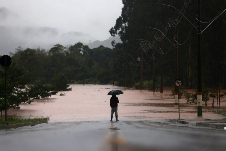 A man stands in front of flooded road near the Taquari River during heavy rains in the city of Encantado in Rio Grande do Sul, Brazil, May 1, 2024. REUTERS/Diego Vara