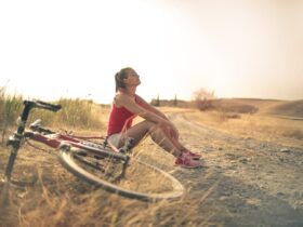Mulher esportiva com bicicleta descansando em uma estrada rural sob a luz do sol - Fotos do Canva