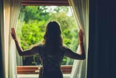Jovem acordando e abrindo as cortinas - Fotos do Canva