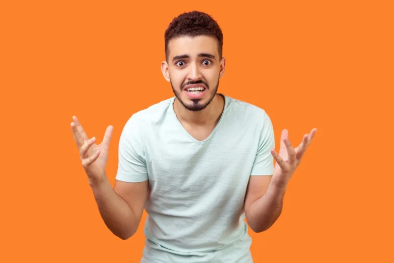 Homem irritado gesticulando em fundo laranja - Fotos do Canva1