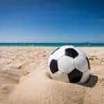 uma bola de futebol esta na areia de uma praia 888757 1190