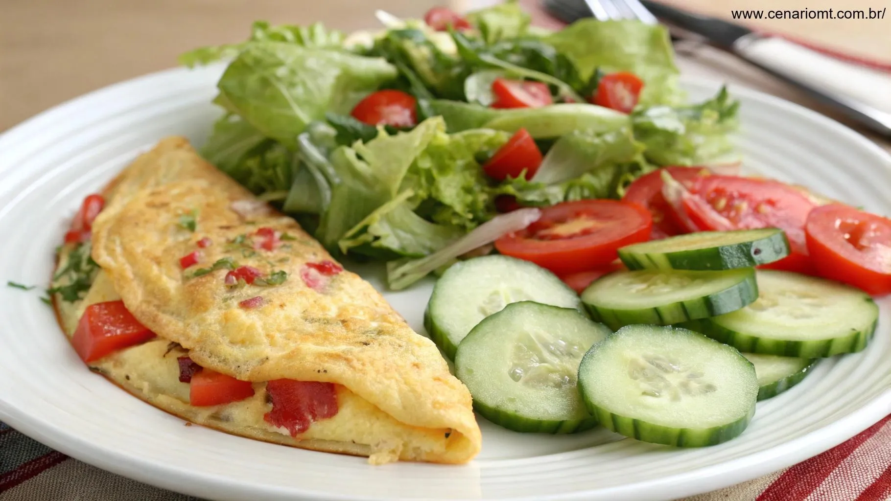 Salada fresca com alface, tomate e pepino, acompanhando uma omelete recheada.
