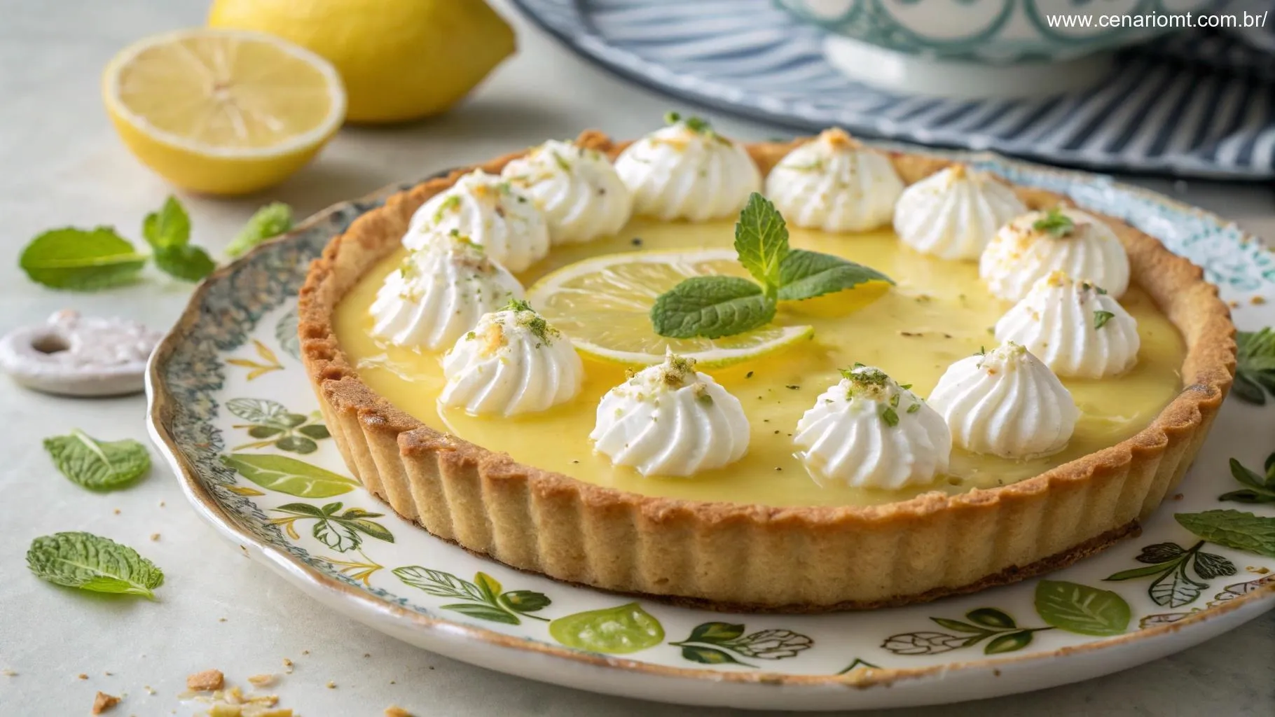 Uma torta de limão lindamente decorada com chantilly, raspas de limão e folhas de hortelã, servida em um prato decorativo.