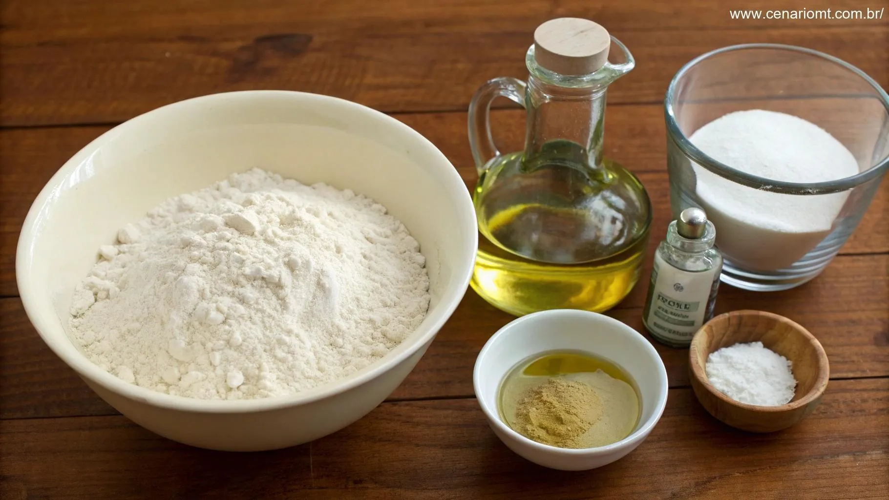 Ingredientes para a massa, incluindo farinha, água, azeite, sal e fermento dispostos em uma mesa de madeira.