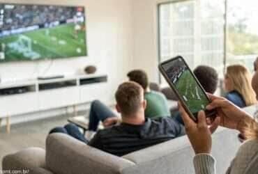Pessoas assistindo um jogo de futebol entre Rayo Vallecano e Real Valladolid em uma televisão e celular, com foco em estatísticas ao vivo.