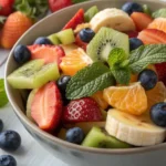 Uma salada de frutas frescas com frutas coloridas como morangos, mirtilos, laranjas, bananas e kiwis, dispostas de forma organizada em uma tigela, com folhas de hortelã como enfeite.