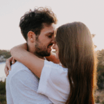 Casal sorridente sob o pôr do sol - Imagem do Canva