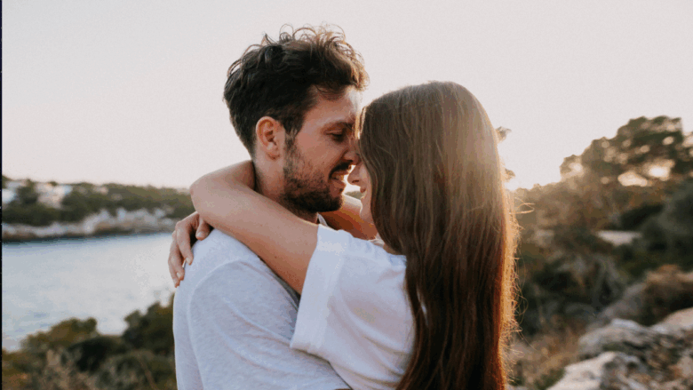 Casal sorridente sob o pôr do sol - Imagem do Canva