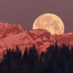 Imagem da Lua Cheia surgindo entre montanhas rochosas, com tons escuros e presença firme, representando foco e responsabilidade, por CenárioMT / Canva
